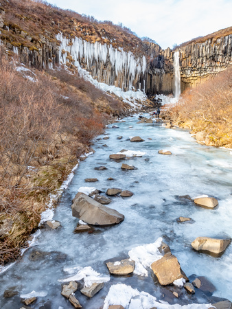 Svartifoss waterfall, one of unique landmark in Iceland, located in Vatnajokull national park, like oasis in black larva sand plain, water freeze in winter seasonの写真素材