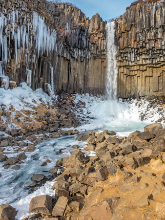 Svartifoss waterfall, one of unique landmark in Iceland, located in Vatnajokull national park, like oasis in black larva sand plain, water freeze in winter seasonの写真素材
