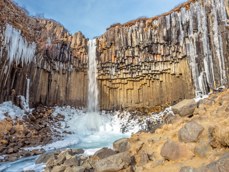 Svartifoss waterfall, one of unique landmark in Iceland, located in Vatnajokull national park, like oasis in black larva sand plain, water freeze in winter seasonの写真素材