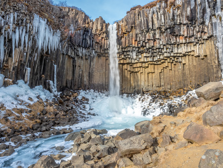 Svartifoss waterfall, one of unique landmark in Iceland, located in Vatnajokull national park, like oasis in black larva sand plain, water freeze in winter seasonの写真素材