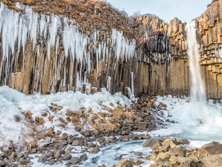 Svartifoss waterfall, one of unique landmark in Iceland, located in Vatnajokull national park, like oasis in black larva sand plain, water freeze in winter seasonの写真素材