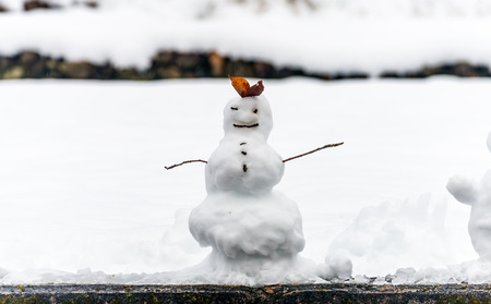 Hand made snowman, built with leaf and branch, at outdoor snow field in early winter season in Japanの写真素材