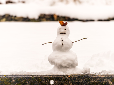 Hand made snowman, built with leaf and branch, at outdoor snow field in early winter season in Japanの写真素材
