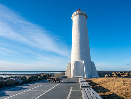 The new active Akranes lighthouse tower at end peninsula in city under blue sky, Icelandの写真素材