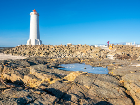 The new active Akranes lighthouse tower at end peninsula in city under blue sky, Icelandの写真素材