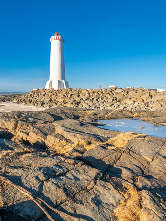 The new active Akranes lighthouse tower at end peninsula in city under blue sky, Icelandの写真素材