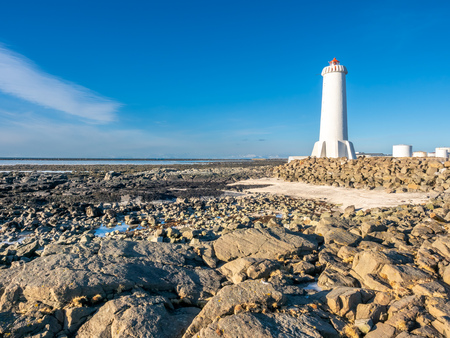 The new active Akranes lighthouse tower at end peninsula in city under blue sky, Icelandの写真素材