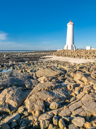 The new active Akranes lighthouse tower at end peninsula in city under blue sky, Icelandの写真素材