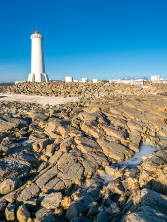 The new active Akranes lighthouse tower at end peninsula in city under blue sky, Icelandの写真素材