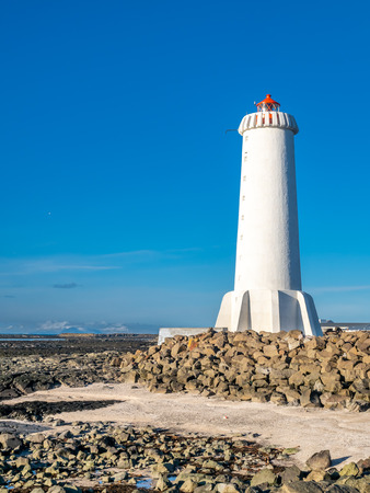 The new active Akranes lighthouse tower at end peninsula in city under blue sky, Icelandの写真素材