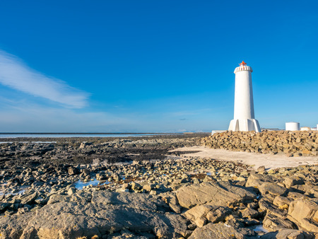 The new active Akranes lighthouse tower at end peninsula in city under blue sky, Icelandの写真素材