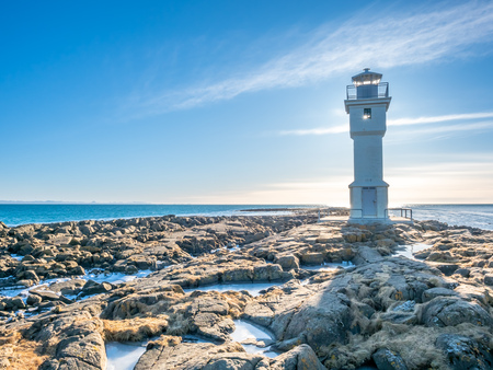 The old inactive Arkranes lighthouse at end of peninsula, was built since 1918, under blue sky, Icelandの写真素材