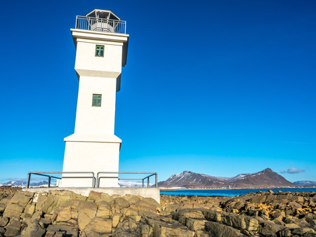 The old inactive Arkranes lighthouse at end of peninsula, was built since 1918, under blue sky, Icelandの写真素材
