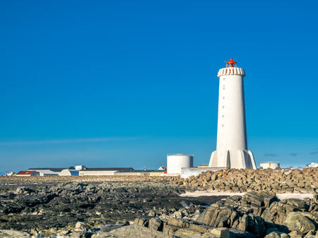 The new active Akranes lighthouse tower at end peninsula in city under blue sky, Icelandの写真素材