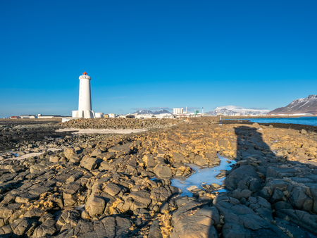 The new active Akranes lighthouse tower at end peninsula in city under blue sky, Icelandの写真素材