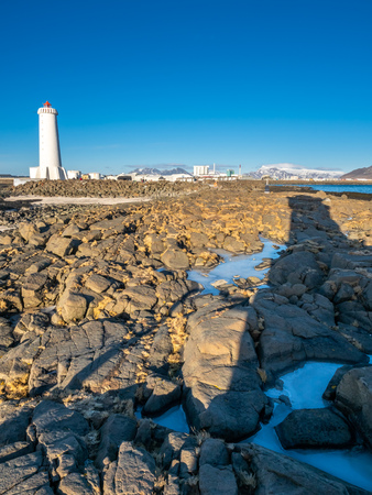 The new active Akranes lighthouse tower at end peninsula in city under blue sky, Icelandの写真素材