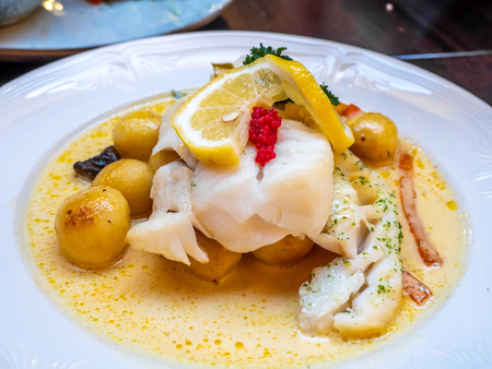 White cod fish with lemon and berry cream sauce on white dish in Iceland restaurantの写真素材
