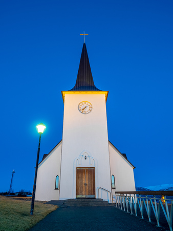 Borganes catholic church, landmark of the city, on small hill in Borganes, Iceland, under blue twilight evening skyの写真素材