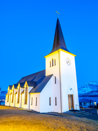 Borganes catholic church, landmark of the city, on small hill in Borganes, Iceland, under blue twilight evening skyの写真素材