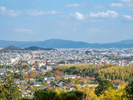 Arashiyama cityscape viewpoint with autumn tree forest under cloudy blue sky with mountains in background, Japanのeditorial素材