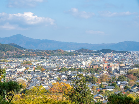 Arashiyama cityscape viewpoint with autumn tree forest under cloudy blue sky with mountains in background, Japanのeditorial素材