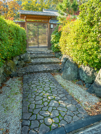 Entrance door with cobblestone pathway in Japanese style with garden decoration in autumn seasonのeditorial素材