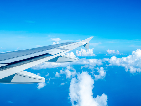 Cloudy blue sky view from aircraft window with its right wingの写真素材