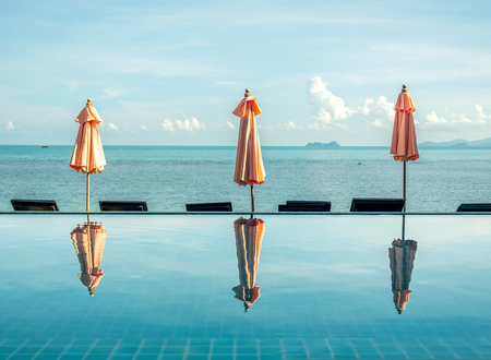 Umbrella reflect with pool water with seascape view under cloudy blue sky in summer season at Samui island, Thailandのeditorial素材