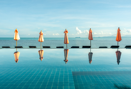 Umbrella reflect with pool water with seascape view under cloudy blue sky in summer season at Samui island, Thailandのeditorial素材