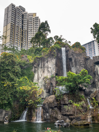 HONG KONG, CHINA - JANUARY 19 : Artificial waterfall in Chinese style garden in Wong Tai Sin Temple with buildings in background, Hong Kong, on January 19, 2018.のeditorial素材