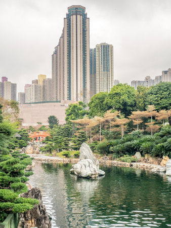 HONG KONG, CHINA - JANUARY 20 : Outdoor garden with tree, pavilion and buildings with pond with skyscraper buildings in background, Hong Kong, China, on January 20, 2018.のeditorial素材