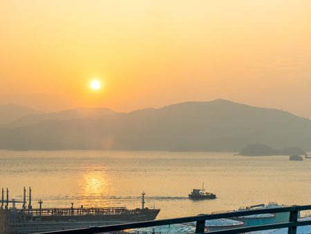 Hong Kong bay with ships under sunset sky and mountains in backgroundの写真素材