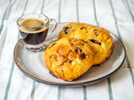 Chunky chewy chocolate chip soft cookies with cup of hot coffee for breakfast, selective focus on melting chocolate chipsの写真素材