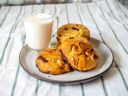 Chunky chewy chocolate chip soft cookies with cup of cold milk for breakfast, selective focus on melting chocolate chipsの写真素材