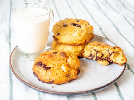 Chunky chewy chocolate chip soft cookies with cup of cold milk for breakfast, selective focus on melting chocolate chipsの写真素材