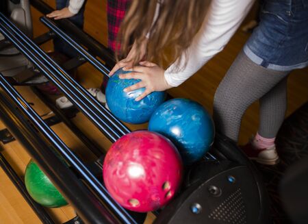 Close-up on teen children hand holding bowling ball against bowling alley - Image. Cheerful Kids are  ready to play - Image.  The bowling alley return machine system concept copy space designの写真素材