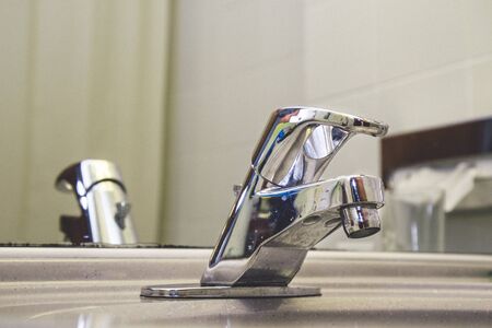 Top close-up , close up photo of steel metal water tap valve control handle in a bathroom . Old used image and blue drops of blue and red indicators . Copy pasteの写真素材