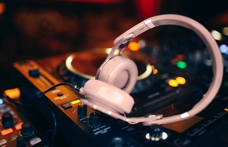 Closeup pair of beige white headphones for DJ.cd mp4 music deejay mixing desk music party in nightclub. Club console for experiments with music.の写真素材