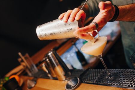 Bartender pouring using strainer White healthy Cocktail drink on a bar counter . Professional view . Trendy stylish alcoholic drink .  Design people and luxury concept service barman in nightclubの写真素材