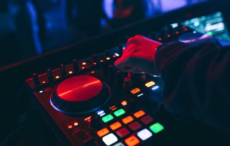 producer  DJ mixer in a nightclub with glowing plays musical rave Dubstep Electronic Trance composition with modern midi controller device in nightclub Live.Musical production process for artists.の写真素材