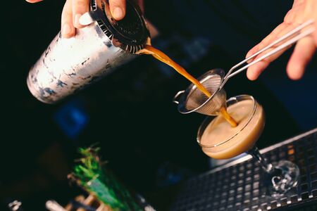 Bartender pouring using strainer White healthy Cocktail drink on a bar counter . Professional view ....
