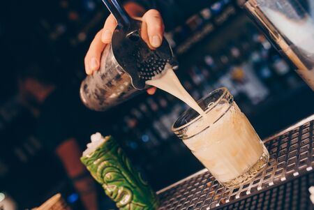 Bartender pouring using strainer White healthy Cocktail drink on a bar counter . Professional view ....