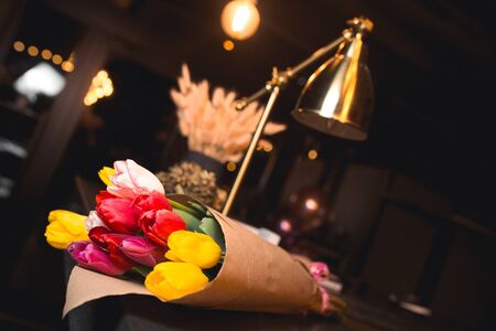 Bunch of Yellow red white  bouquet of tulips laying in nightclub restaurant. Fresh spring Greeting card for Saint Valentine's template February 14, Mother's Day, 8 March Teacher's Day の写真素材