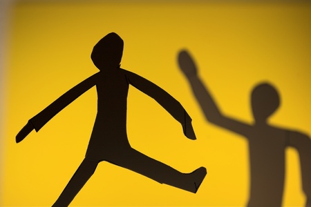 people silhouette cut in small rudimentary figures  in paper , shot with colorfull backgroundの写真素材
