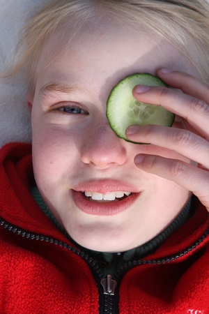 close up of child face with cucumber slice on the eyesの写真素材