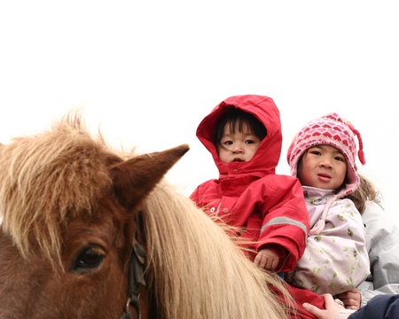 two children riding a horse in winterの写真素材