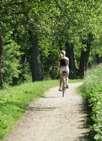 girl on bike on a forest path in denmarkの写真素材