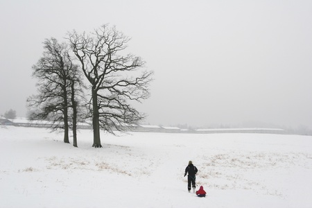 family  in winter in denmark, mother and child in the snow a foggy grey day