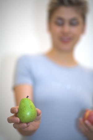 woman hesitating : holding a pear and  an apple の写真素材