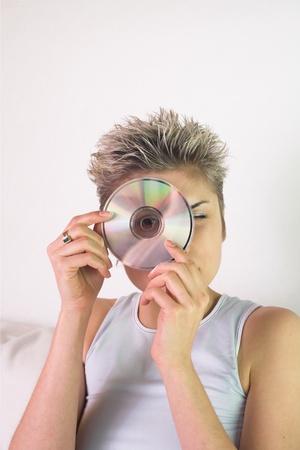 Blond short hair woman woman with white Tshirt looking through a CD holeの写真素材
